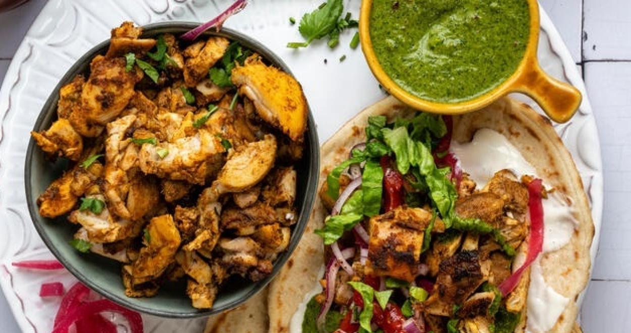 Chicken Schwarma auf einem Teller mit Fladenbrot und weiteren Beilagen