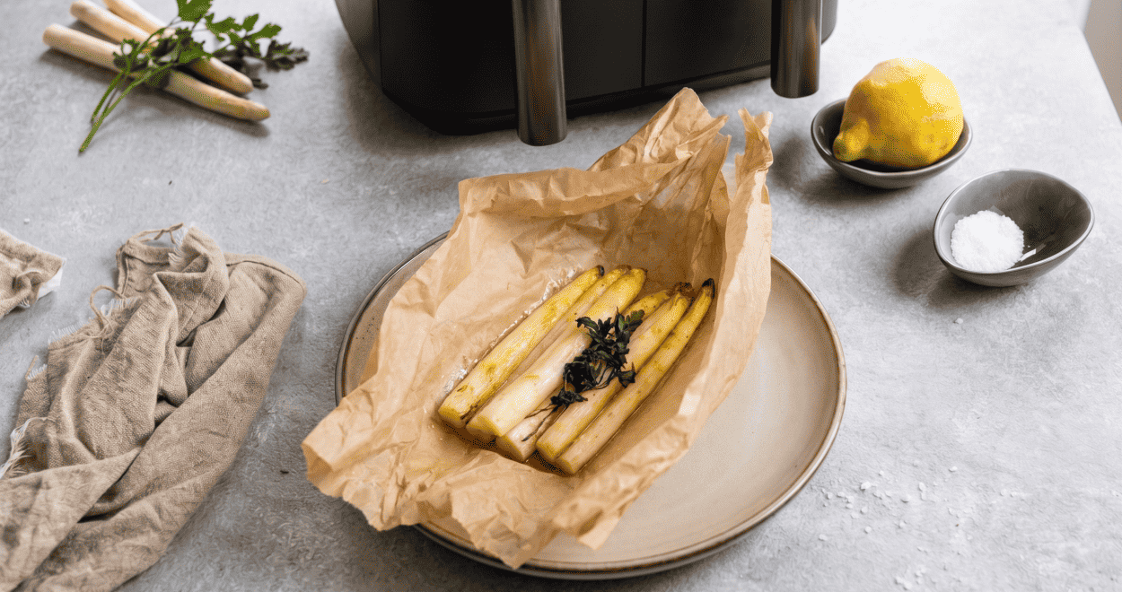 Spargel mit Butter auf einem Teller vor einem Airfryer