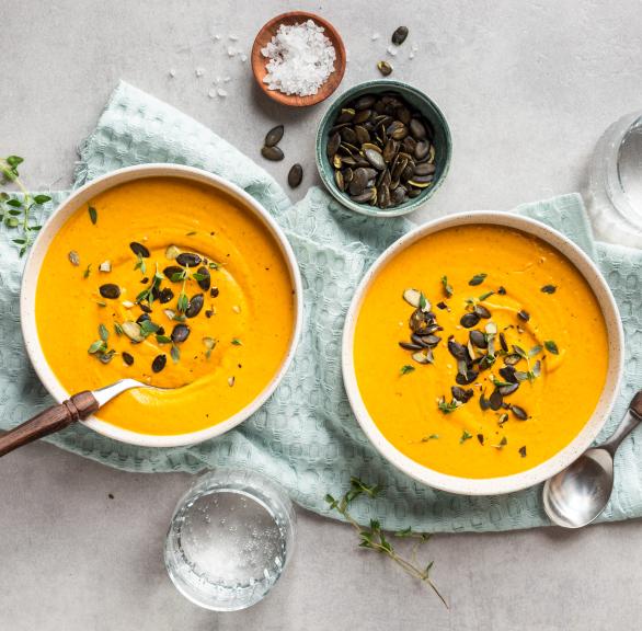 Kürbissuppe mit Kernen in zwei Schüsseln.
