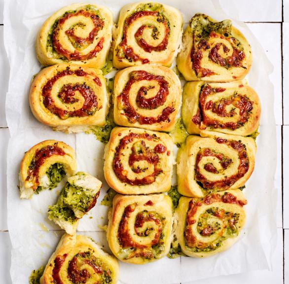Selbstgebackene Pizzarollen mit Pesto und Tomatensoße auf einem Stück Backpapier