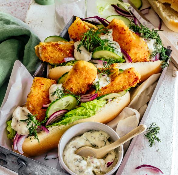 Hot Dogs gefüllt mit Fischstäbchen, Salat und Remoulade auf einem Teller