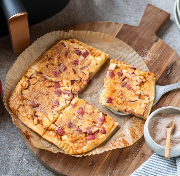 Apfelpfannkucen angeschnitten auf einem runden Backpapierzuschnitt vor einer Heißluftfritteuse