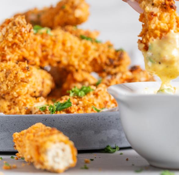 Tofu-Nuggets in Cornflakes-Panade werden in eine Sauce gedippt