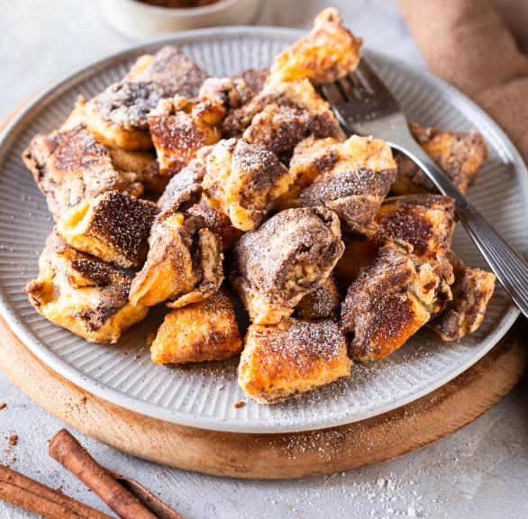 Kaiserschmarren auf einem Teller, daneben Zimt-Zucker-Mischung