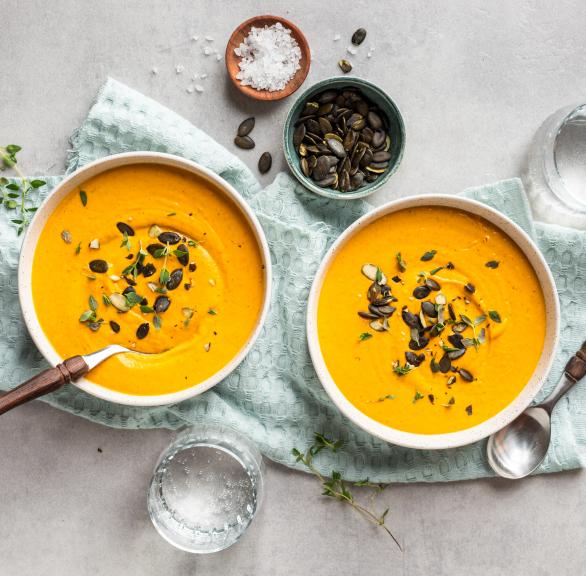 Kürbissuppe mit Kernen in zwei Schüsseln.