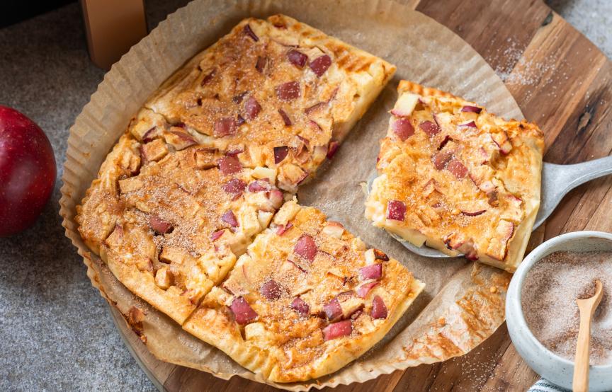 Apfelpfannkucen angeschnitten auf einem runden Backpapierzuschnitt vor einer Heißluftfritteuse