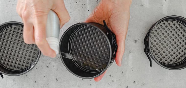 Man sieht wie Mini-Backformen für due Heißluftfritteuse mit Öl eingesprüht werden