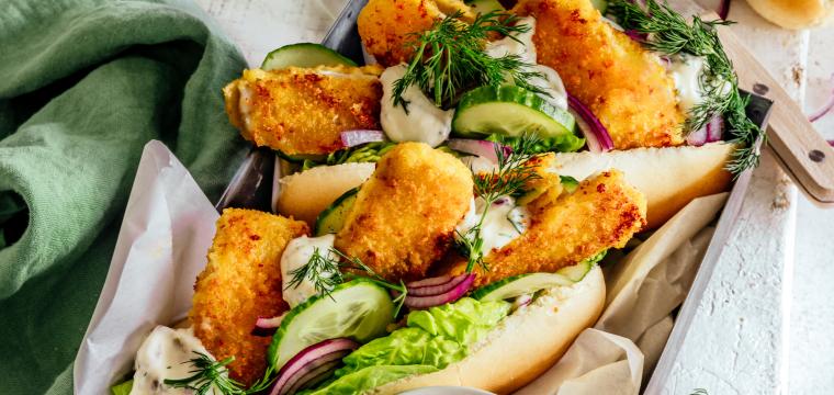 Hot Dogs gefüllt mit Fischstäbchen, Salat und Remoulade auf einem Teller