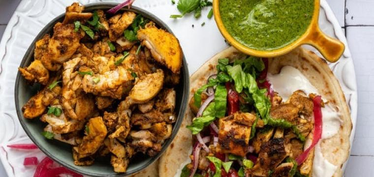 Chicken Schwarma auf einem Teller mit Fladenbrot und weiteren Beilagen Chicken Schwarma auf einem Teller mit Fladenbrot und weiteren Beilagen