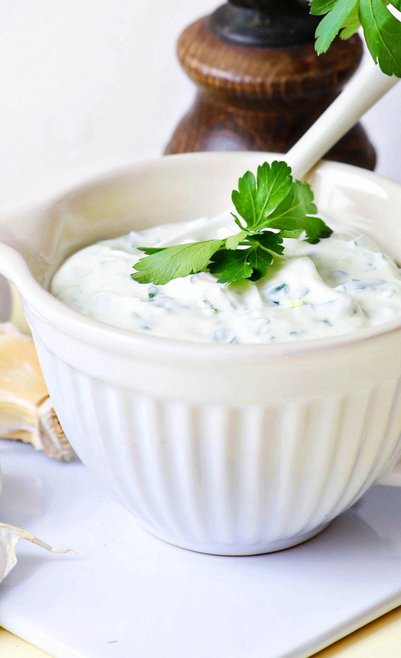 Knoblauchsoße in einem Schälchen mit Kräutern garniert.