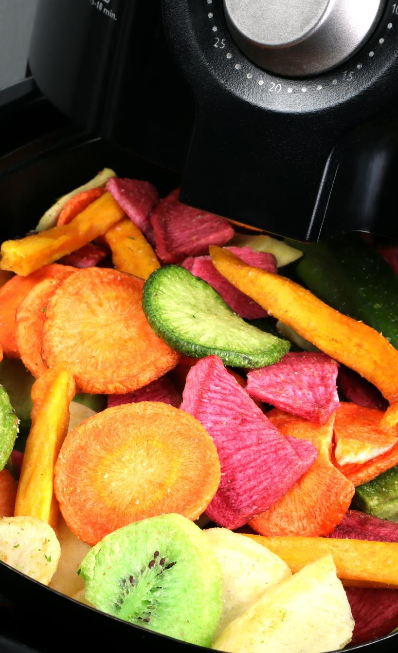 Schublade einer geöffneten Heißluftfritteuse mit einem bunten Mix aus Gemüse