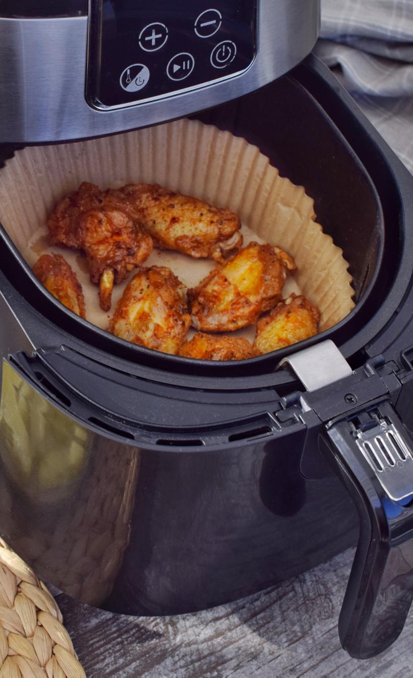 Mehrere Lebensmittel auf einem Tisch, daneben eine geöffnete Heißluftfritteuse