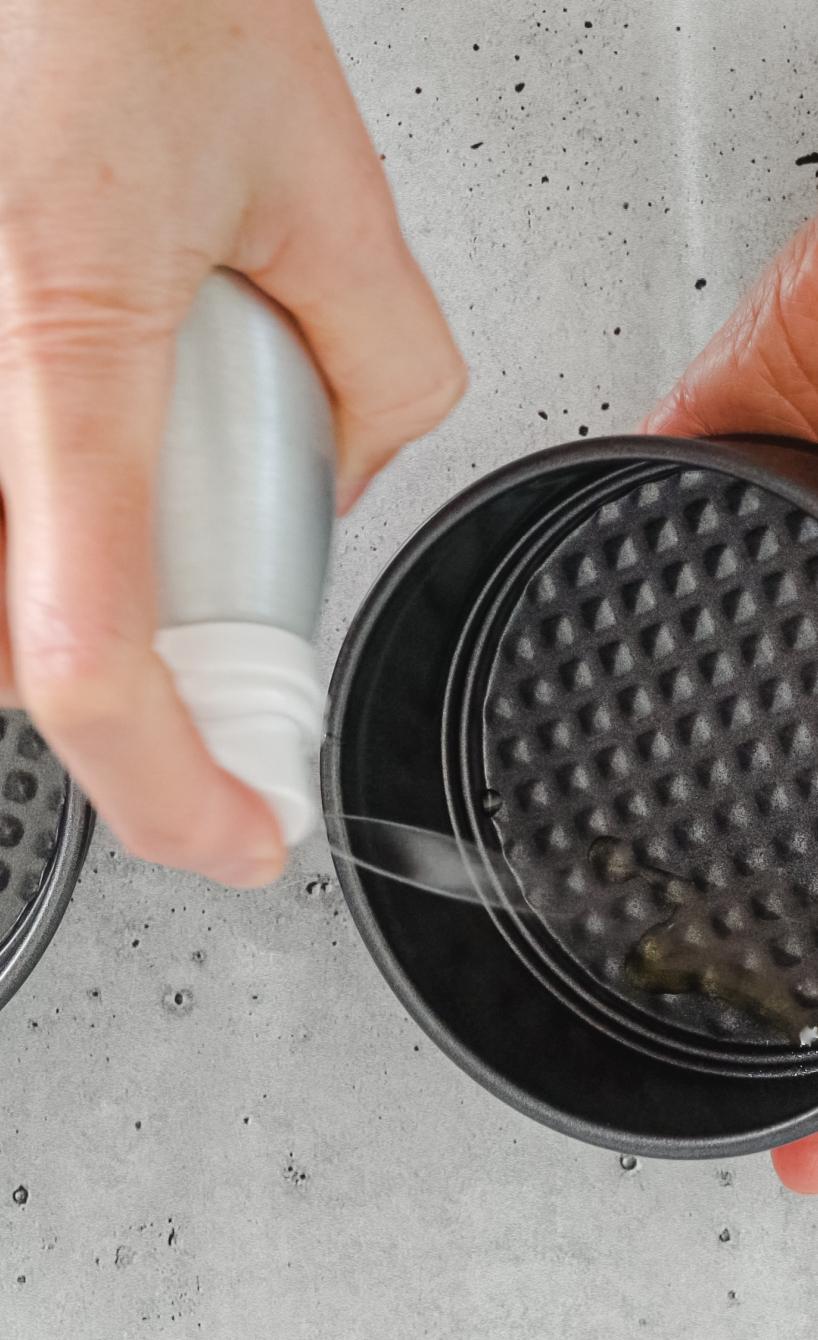 Man sieht wie Mini-Backformen für due Heißluftfritteuse mit Öl eingesprüht werden