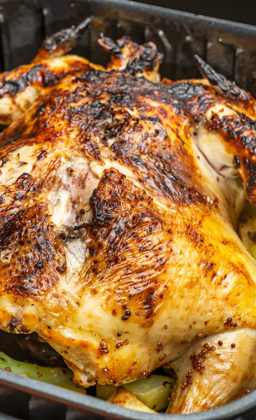 Garkorb einer XL-Heißluftfritteuse mit Kartoffeln und einem ganzen Hähnchen