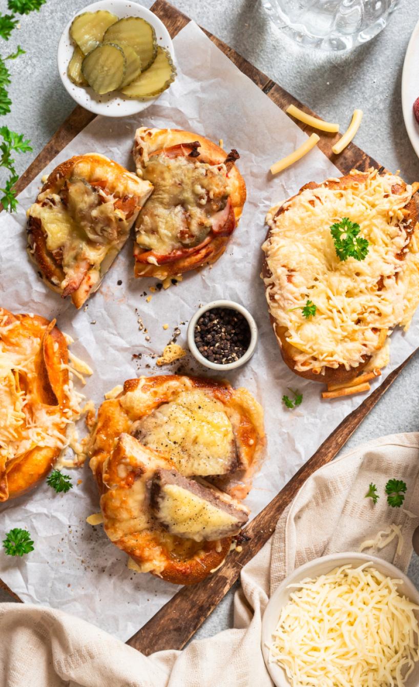 Verschieden getoppte Laugenbrezeln auf einem Tisch neben einer Heißluftfritteuse