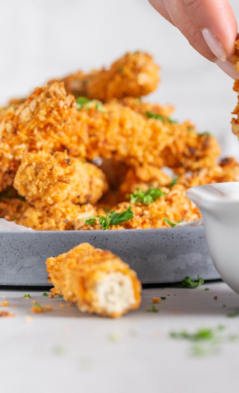 Tofu-Nuggets in Cornflakes-Panade werden in eine Sauce gedippt