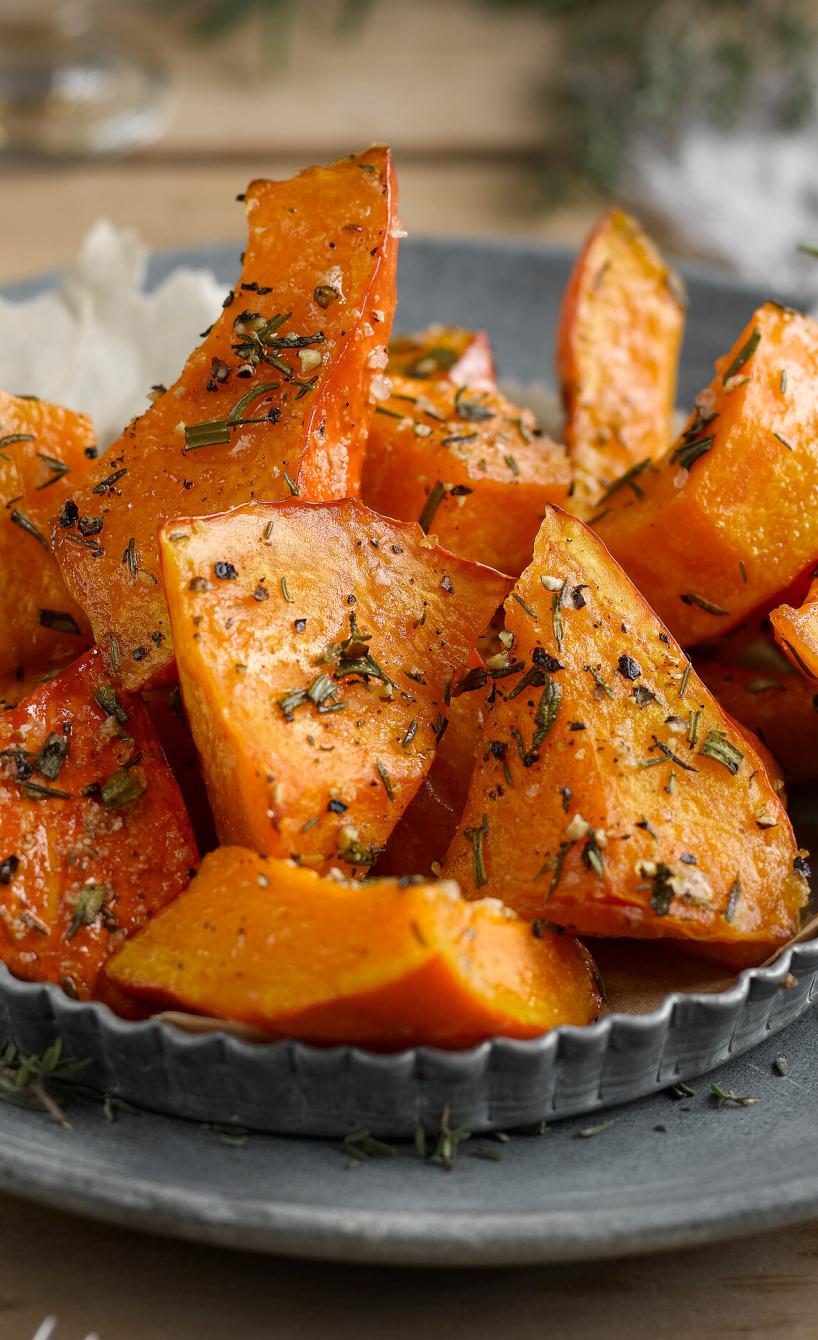 Kürbisspalten auf einem Teller mit frischen Kräutern