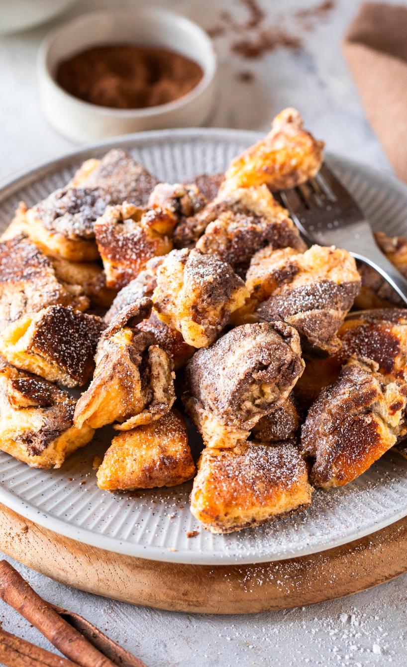 Kaiserschmarren auf einem Teller, daneben Zimt-Zucker-Mischung