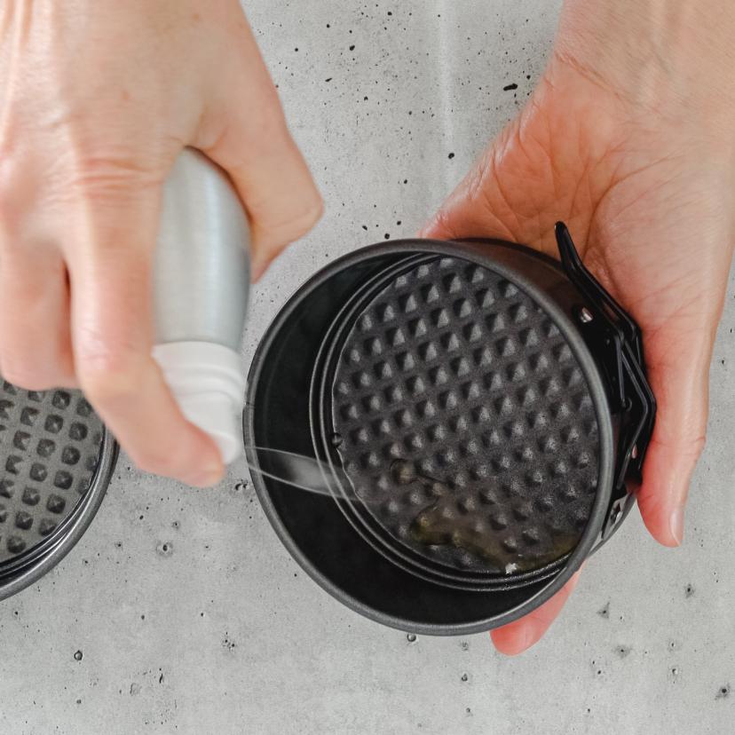 Man sieht wie Mini-Backformen für due Heißluftfritteuse mit Öl eingesprüht werden